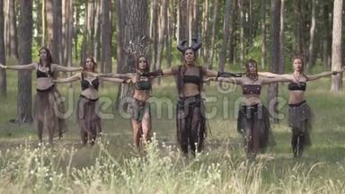 一群身穿化妆和神秘服装的女舞者在彩色烟雾中翩翩起舞。 森林